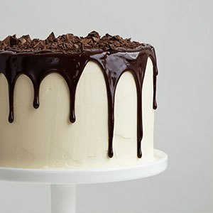 A delicious chocolate cake covered in white chocolate frosting with chocolate
      ganache icing.