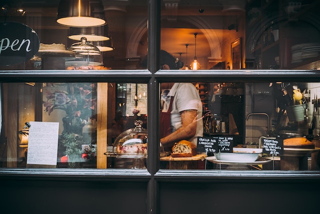 A baker working on creating new baked goods behind a window.