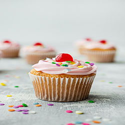 A singular vanilla cupcake with colorful frosting and cherry on top.